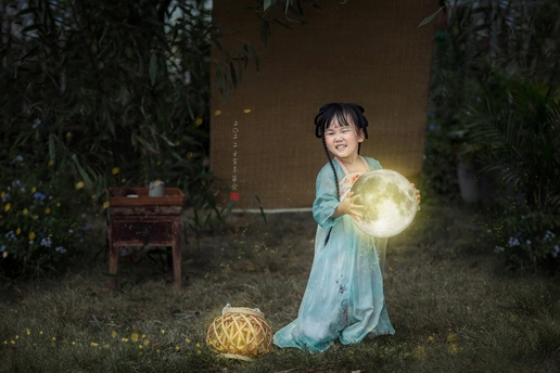 一个穿着亮色连衣裙的年轻女孩晚上在花园里玩球