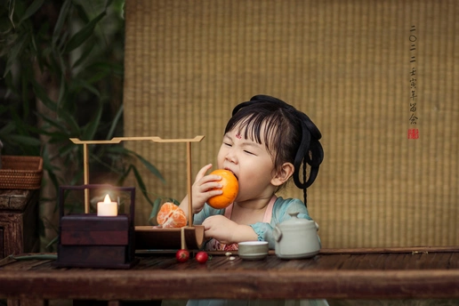 一个坐在桌子旁吃小桔子的小女孩