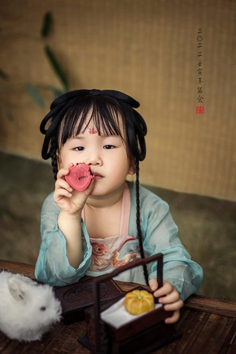 一个小女孩在桌子旁吃东西 脸上戴着一个小娃娃