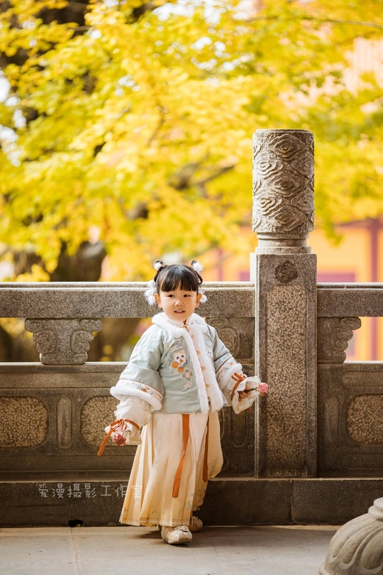 一个穿着日本传统服装的小孩子站在一座寺庙前面。