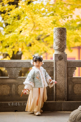 一个穿着日本传统服装的小孩子站在一座寺庙前面。