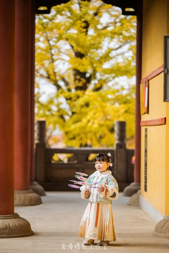 一个小女孩穿着传统服装站在一座小建筑前
