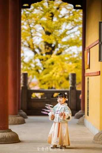 一个小女孩穿着传统服装站在一座小建筑前