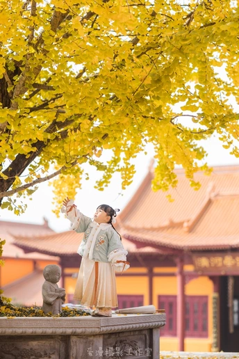 一位穿着和服的女性在寺庙前拍下了一尊女性雕像 雕像站在一棵树下。