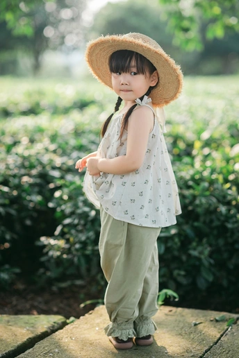 一个小女孩戴着小帽子站在花园里