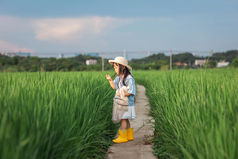 一位年轻女子手持雨伞站在绿草地上