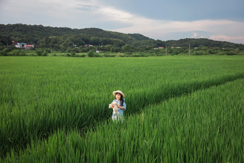 一位年轻女子和一个小女孩站在绿野中