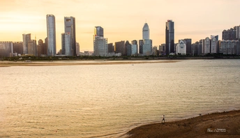 夕阳下的城市照片 天线上有摩天大楼 前景是一条河流。