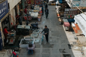一个男人走在鱼市场旁边的街道上