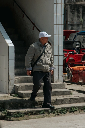 一位戴着白帽子的老人正走下台阶