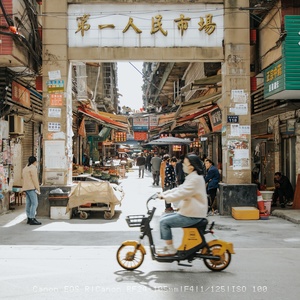 一位女士骑着滑板车在亚洲城市的狭窄巷子里