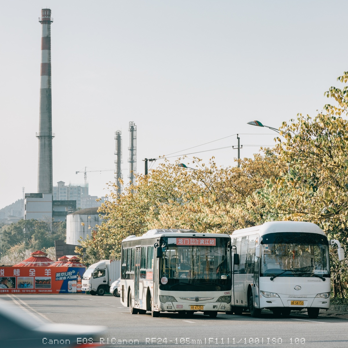 一辆白色公交车在靠近工厂的道路上行驶 道路上还有其他交通。