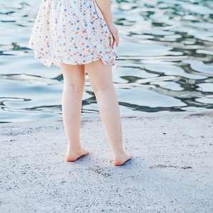 一位年轻女子站在湖边 双脚浸在水中