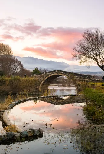 夕阳下 一座古老的石桥横跨在小溪上