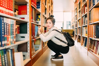 一个在图书馆里的年轻女子正在书架上拿一本书。