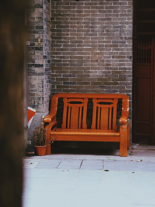 一张橙色长凳坐在红砖建筑前 旁边是红门。