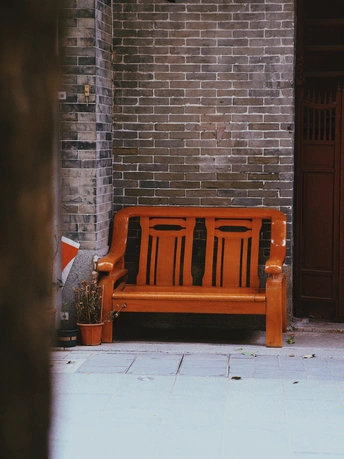 一张橙色长凳坐在红砖建筑前 旁边是红门。