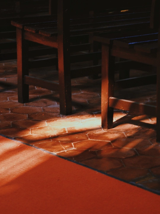 阳光照耀在一张木制桌子和红色地板的教堂里