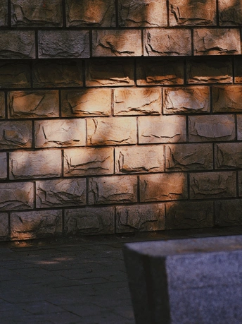 坐在砖墙前的木凳上 由灯发出的光照亮。