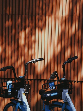 几辆蓝色的自行车靠在墙上 墙上有阴影。