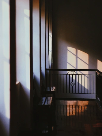 阳光透过窗户照进一个有楼梯和二楼有长凳的黑暗房间