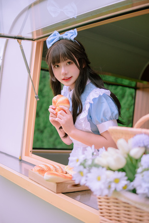 一位年轻女子拿着一个甜甜圈和一篮子食物靠近窗户