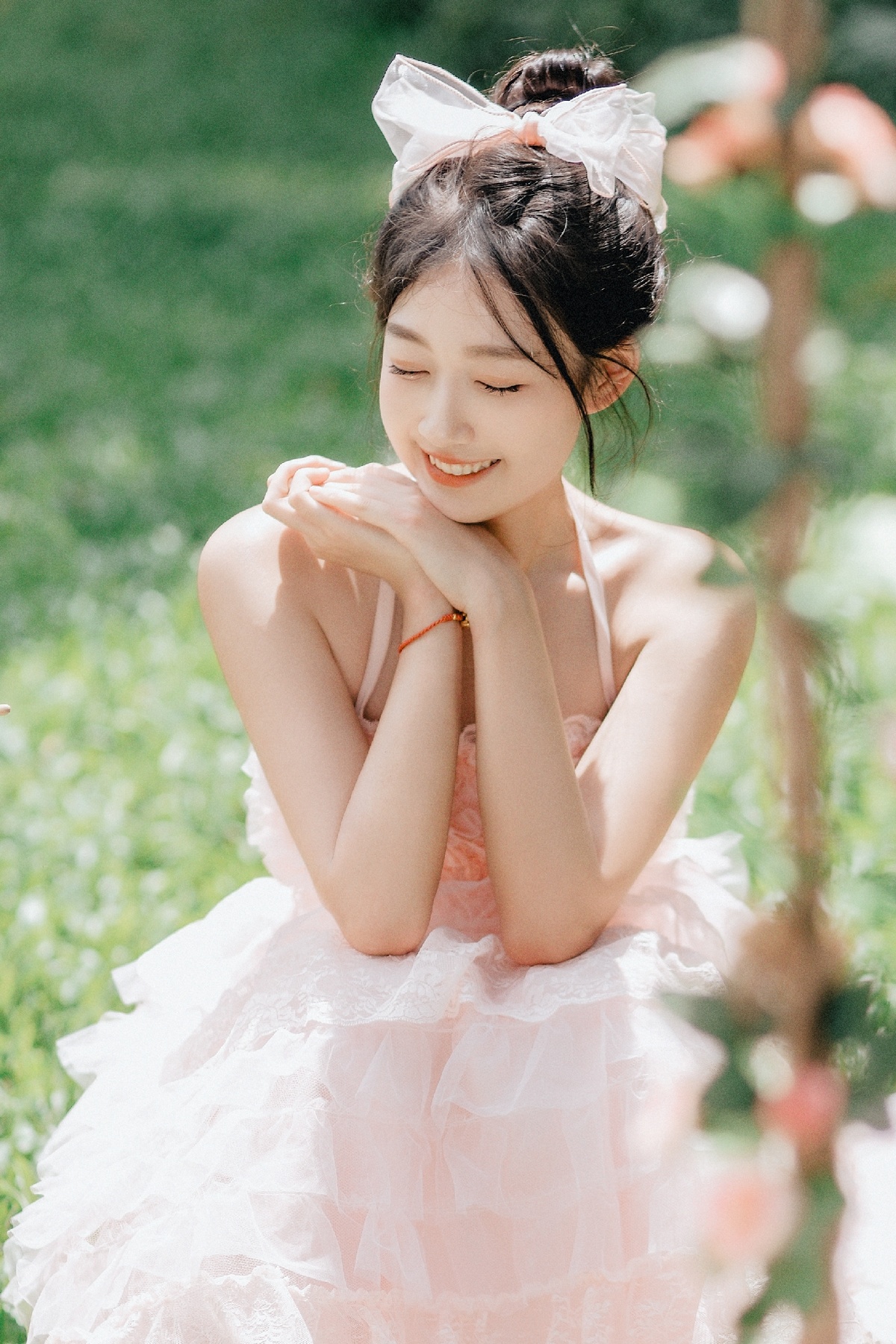 美丽的年轻女子穿着粉红色裙子坐在花丛中