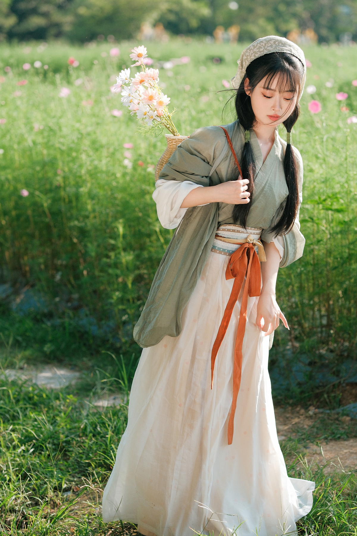 一位穿着白色连衣裙的年轻女子手持雨伞站在花丛中。