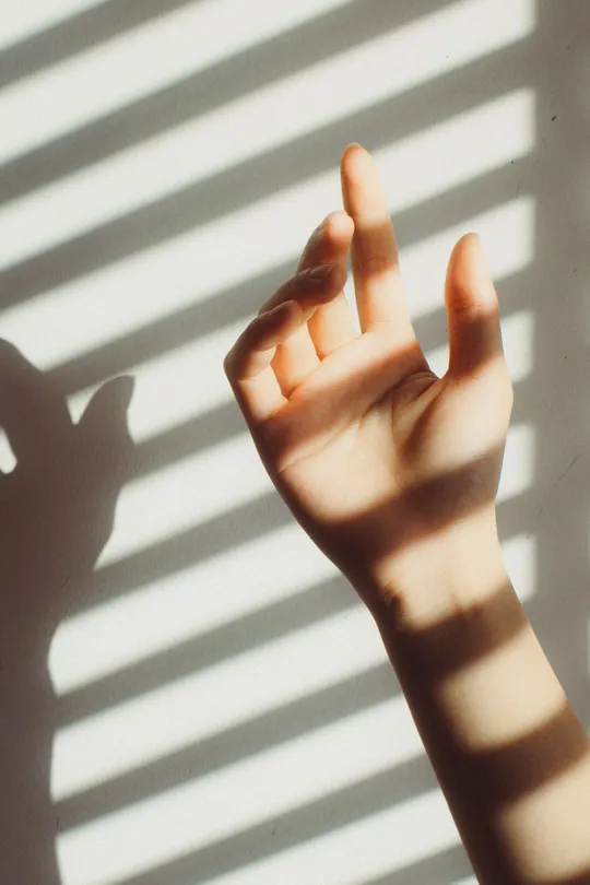 墙上的手影 窗帘阻挡着阳光 阳光透过窗帘洒在手上