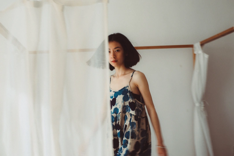 一个穿着连衣裙的年轻女子站在床边