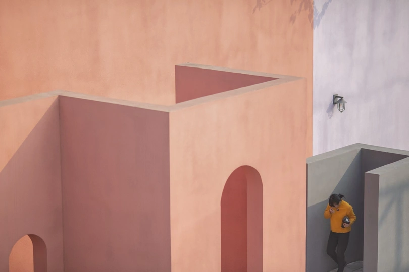 一个人站在一栋粉红色建筑前面