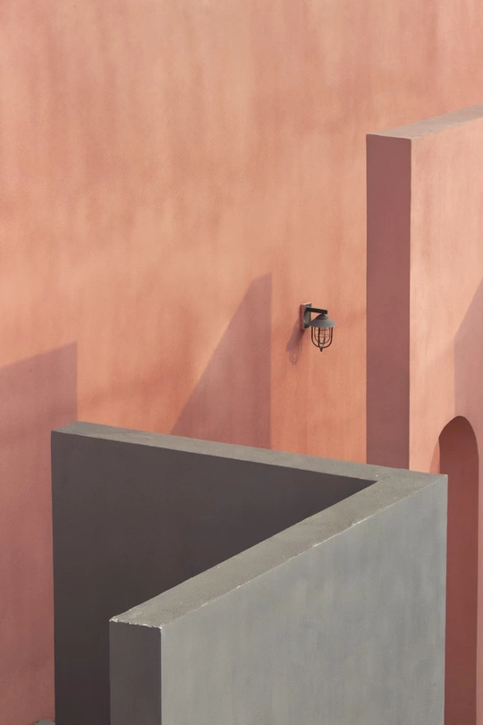 一座带有粉红色墙壁和楼梯投射出阴影的房子