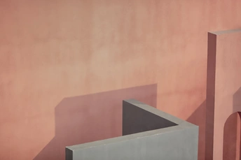 粉红色墙壁上投射出一个混凝土物体