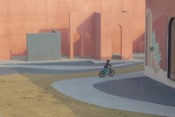 一个人骑自行车在粉色建筑前面