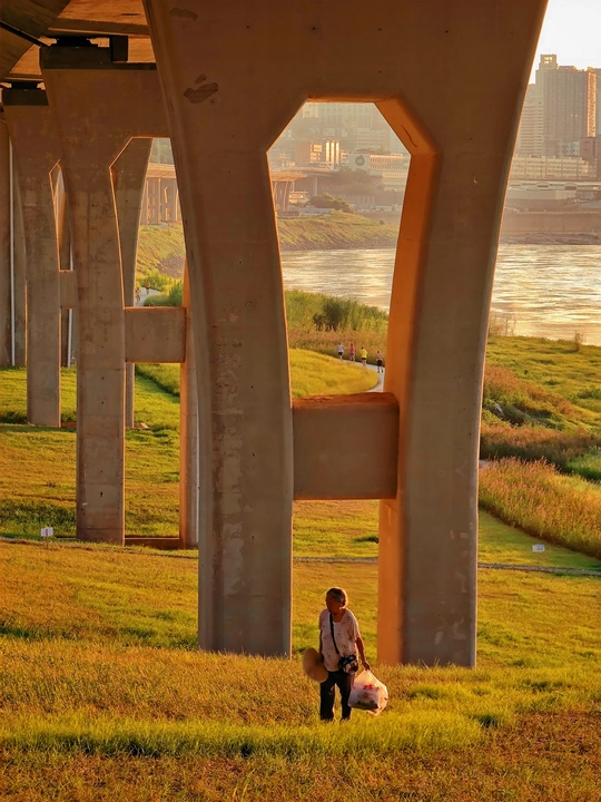 一男一女坐在桥下河边的草地上