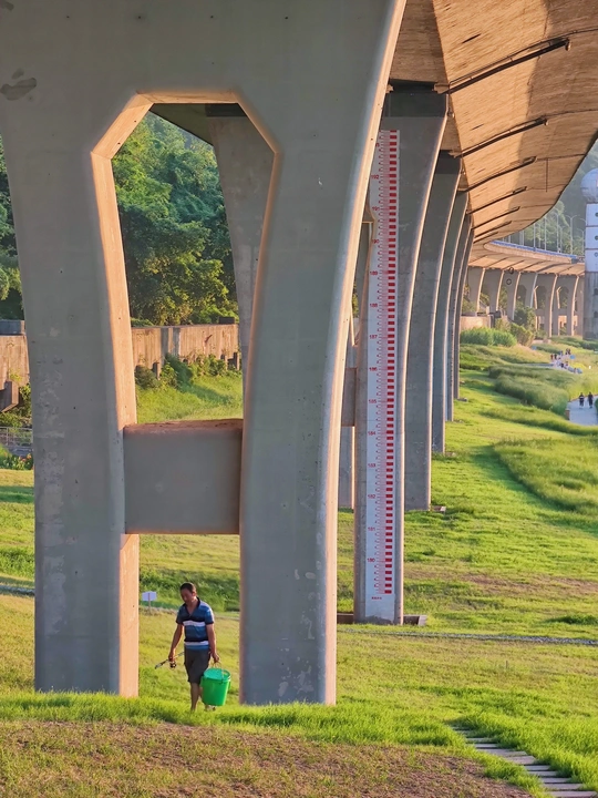 一个女人提着一桶水走在桥下