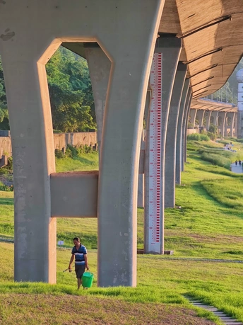 一个女人提着一桶水走在桥下