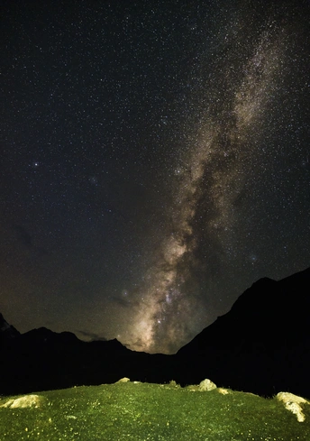 夜晚的绿色田野 天空中有星星和星系