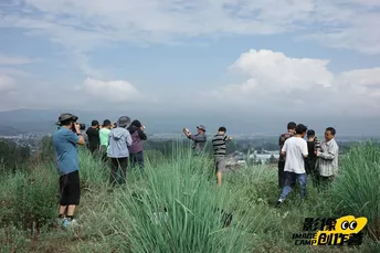 站在山丘上的人们正在拍摄天空和草地。