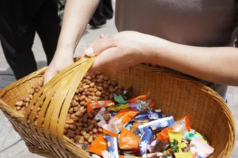 一位女士在街上 carrying a basket full of snacks and a bag