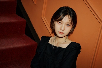 一位穿着黑色连衣裙的年轻女子站在楼梯前