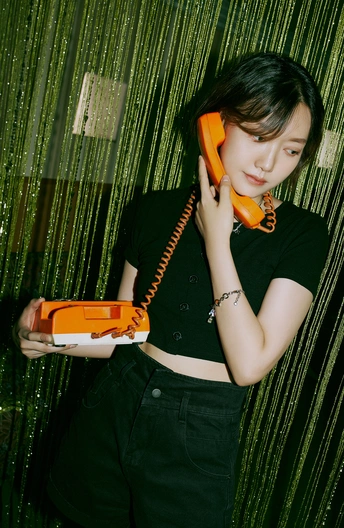 一位年轻女子正在耳边拿着橙色手机