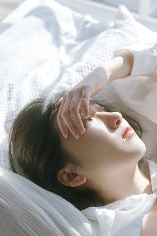 一个年轻女子躺在床上 手搭在她的头上