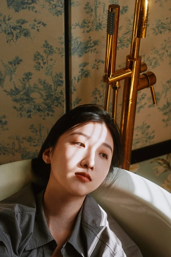 一个穿着衬衫和领带坐在有花卉图案的房间里的年轻女子