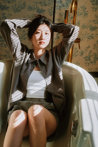 一个穿着西装的年轻女子坐在带浴缸和厕所的浴室里的椅子上