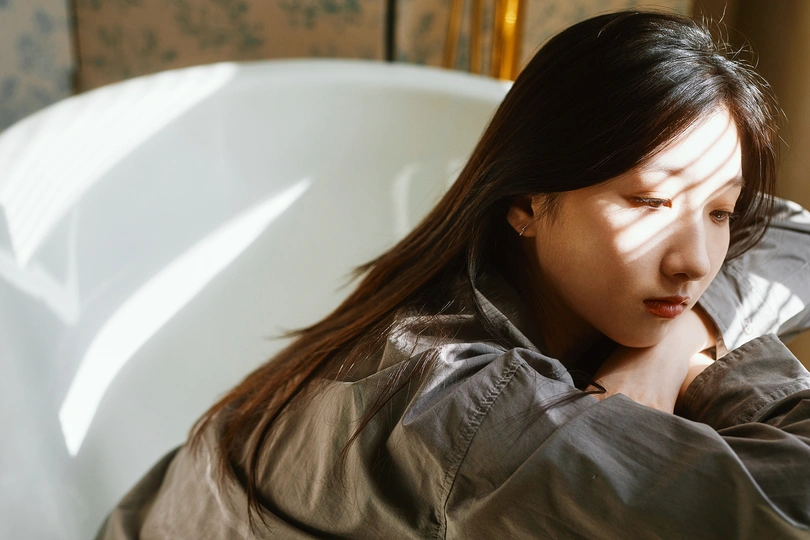 一个年轻女子坐在白色浴缸里 看着她的头发