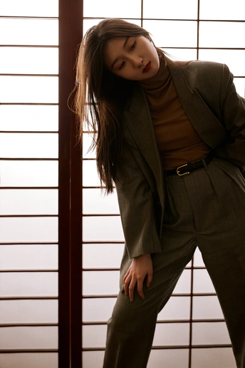 一位年轻女子穿着西装靠在窗户上