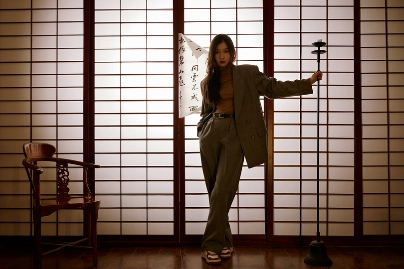 一个妇女站在一个带有椅子和雨伞的房间里