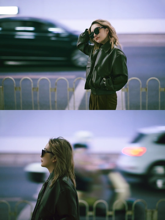 一个穿皮夹克的女人走在汽车旁边的一条街上