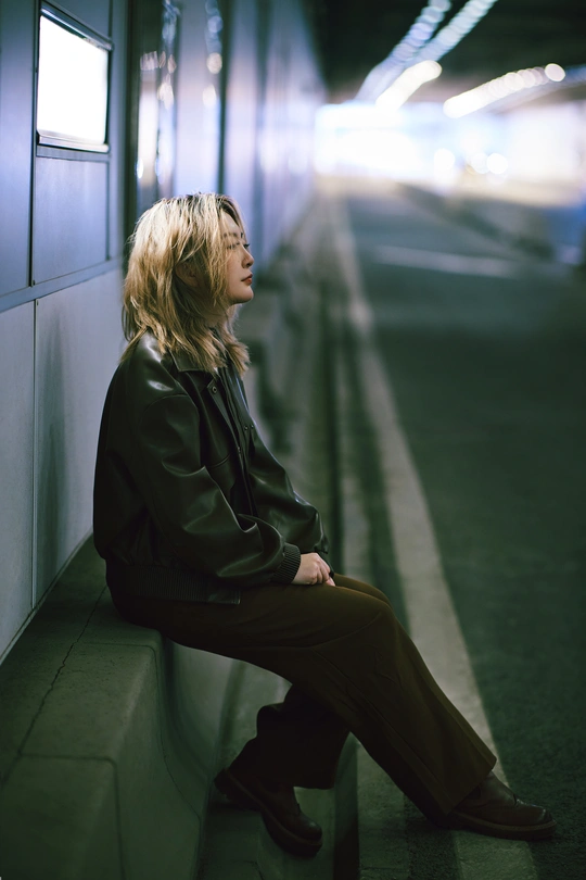一位妇女坐在墙边的长椅上等待火车